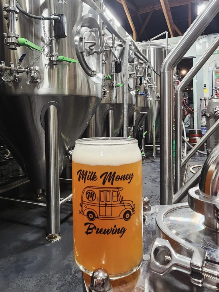 Pint of beer in front of the brewing equipment at Milk Money Brewing